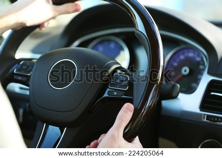 Man\'s hands on a steering wheel