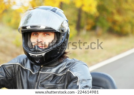 Biker man in black helmet sits on bike