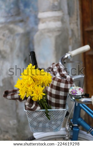 Old bicycle with flowers and checkered blanket in metal basket on old wall background