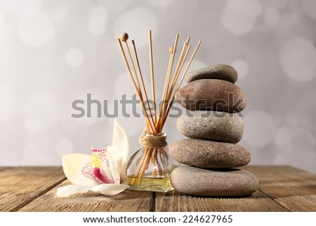 Spa stones, aroma sticks and white orchid on wooden table on light background