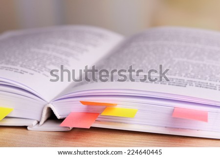 Book with bookmarks on table on bright background