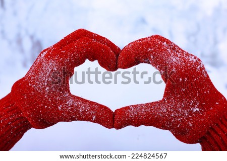 Woman\'s hands in red gloves on winter natural background