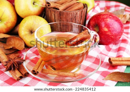Composition of  apple cider with cinnamon sticks, fresh apples and autumn leaves on wooden table, on bright background