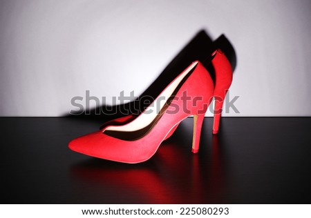 Pair of woman\'s red shoes on floor on light wall background