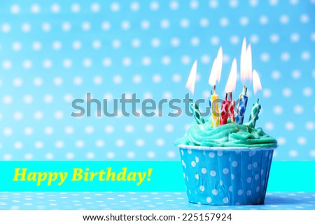 Delicious birthday cupcake on blue background