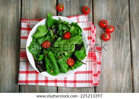 Fresh green salad in bowl on wooden table