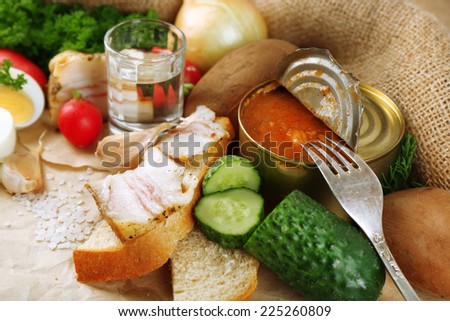 Bacon, fresh vegetables, boiled egg and bread on paper, glass with vodka on wooden background. Village breakfast concept.