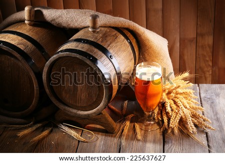Beer barrel with beer glass on table on wooden background