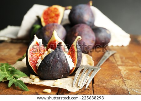 Ripe sweet fig with cottage cheese on wooden table, on dark background