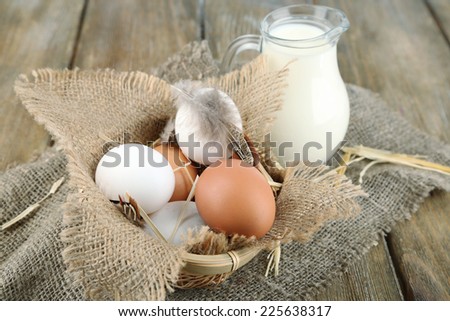Eggs and fresh milk in glass jug, on wooden background. Organic products concept