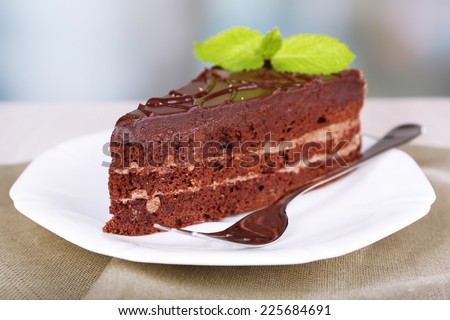 Piece of chocolate cake on plate on wooden table on natural background
