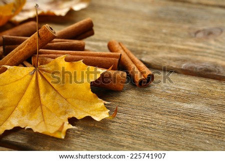 Cinnamon sticks with yellow leaves on wooden background