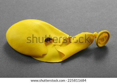 Popped yellow balloon on paper background