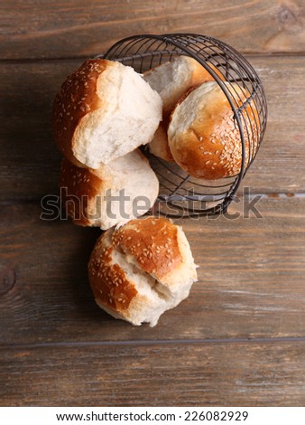 Tasty buns with sesame on color wooden background