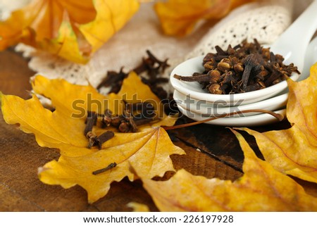 Carnation in spoon with yellow leaves on wooden background