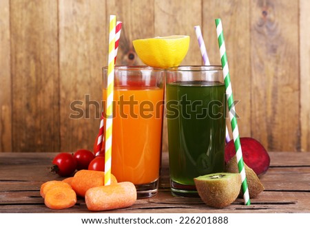 Fruit and vegetable juice in glasses and fresh fruits and vegetables on table on wooden background