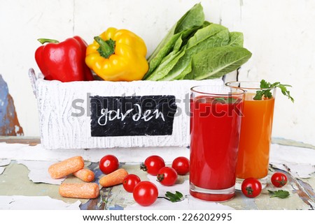 Vegetable juice and fresh vegetables in wooden box on wooden table on wall background