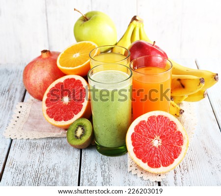 Fruit and vegetable juice and fresh fruits on napkin on wooden table on wooden wall background