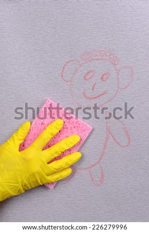 Hand in glove wiping children drawing on wallpaper