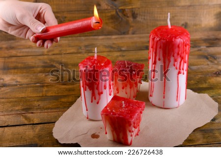 Process of decorating candles for Halloween party. Female hand holding burning candle, close-up