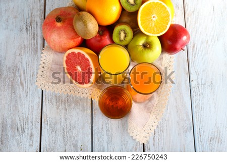 Fruit and vegetable juice and fresh fruits on napkin on wooden background