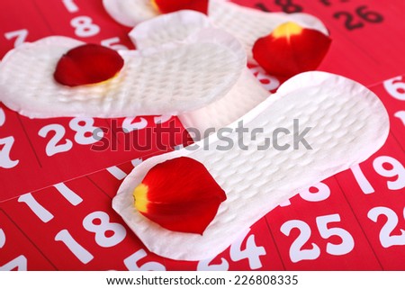 Sanitary pads and rose petals on calendar background