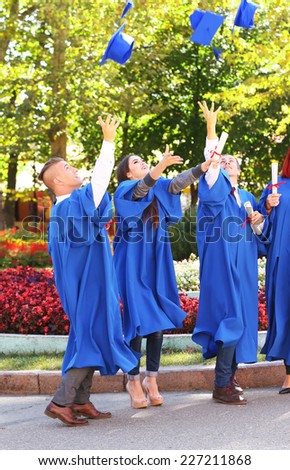 Students throwing graduation hats in air, outdoors