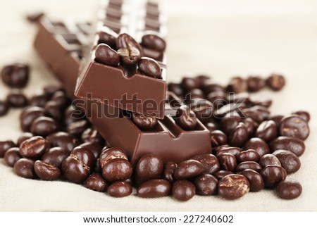 Coffee beans with chocolate glaze and dark chocolate on grey tablecloth