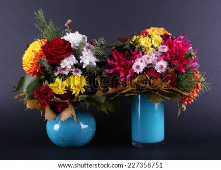 Flower bouquets in blue vases on light wooden background