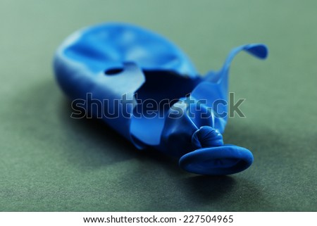 Popped blue balloon on paper background