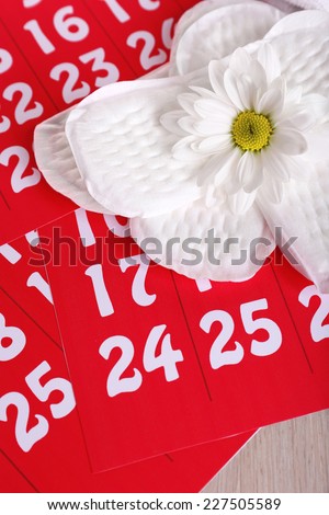 Sanitary pads and white flower on red calendar background