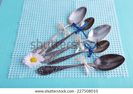 Metal spoons on white napkin on light blue background