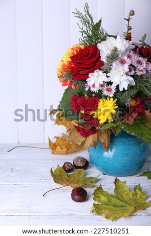 Flower bouquet in blue vase on light wooden background