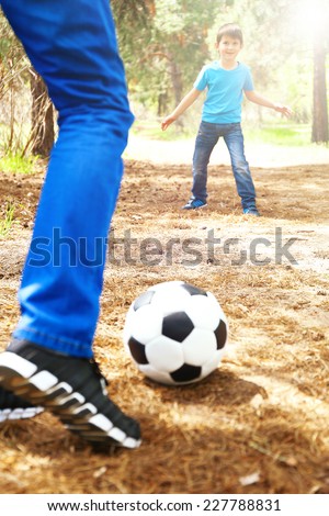 Happy dad and son playing football in the park