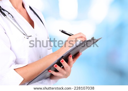 Young beautiful doctor holding folder on hospital background