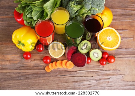 Fruit and vegetable juice in glasses and fresh fruits and vegetables on background