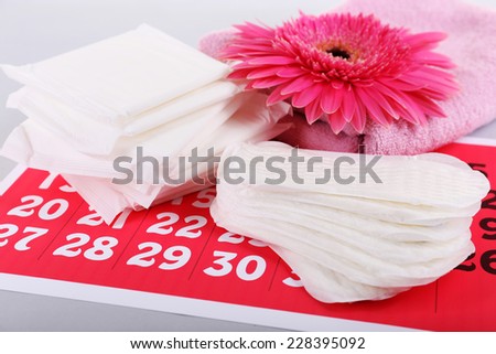 Sanitary pads, calendar, towel and pink flower on light background