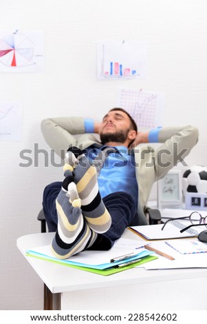 Confident businessman holding his legs in funny socks on desk