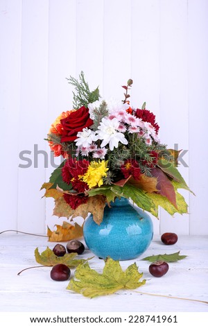 Flower bouquet in blue vase on light wooden background
