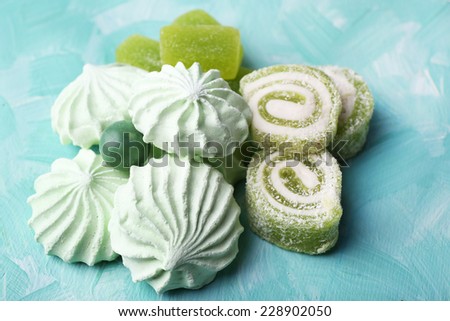 Mint color meringues and mint jelly candies on color background