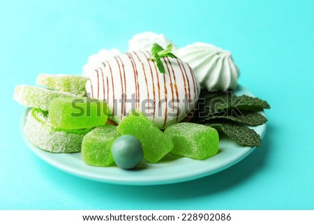 Mint color meringues, mint candies and tasty cake on color background