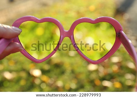 Vision concept. Glasses in hand on green grass background