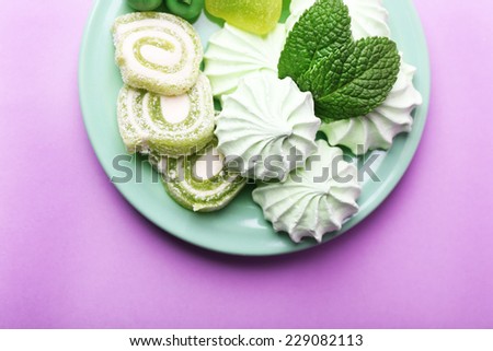 Mint color meringues, mint candies and tasty cake on color background