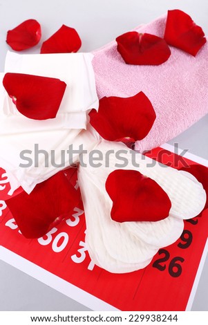 Sanitary pads, calendar, towel and white flowers on light background