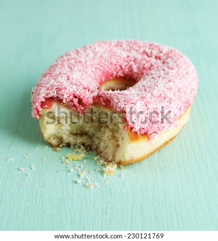 Bitten delicious donut on wooden table close-up