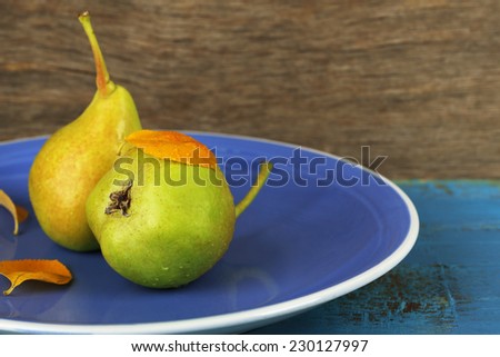 Ripe tasty pears on plate, on wooden table