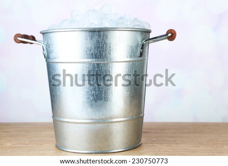 Ice bucket on wooden table on light background
