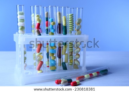 Different color drugs in test tubes, on wooden table, on color background