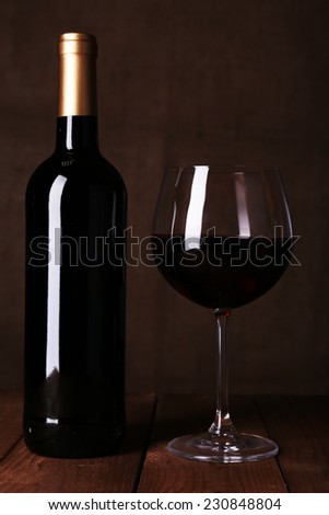 Red wine glass and bottle of wine on dark background