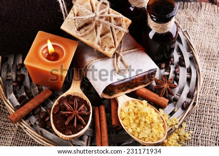 Organic soap with coffee beans, sea salt and milled coffee in wooden spoons on wicker mat, on wooden background, Coffee spa concept